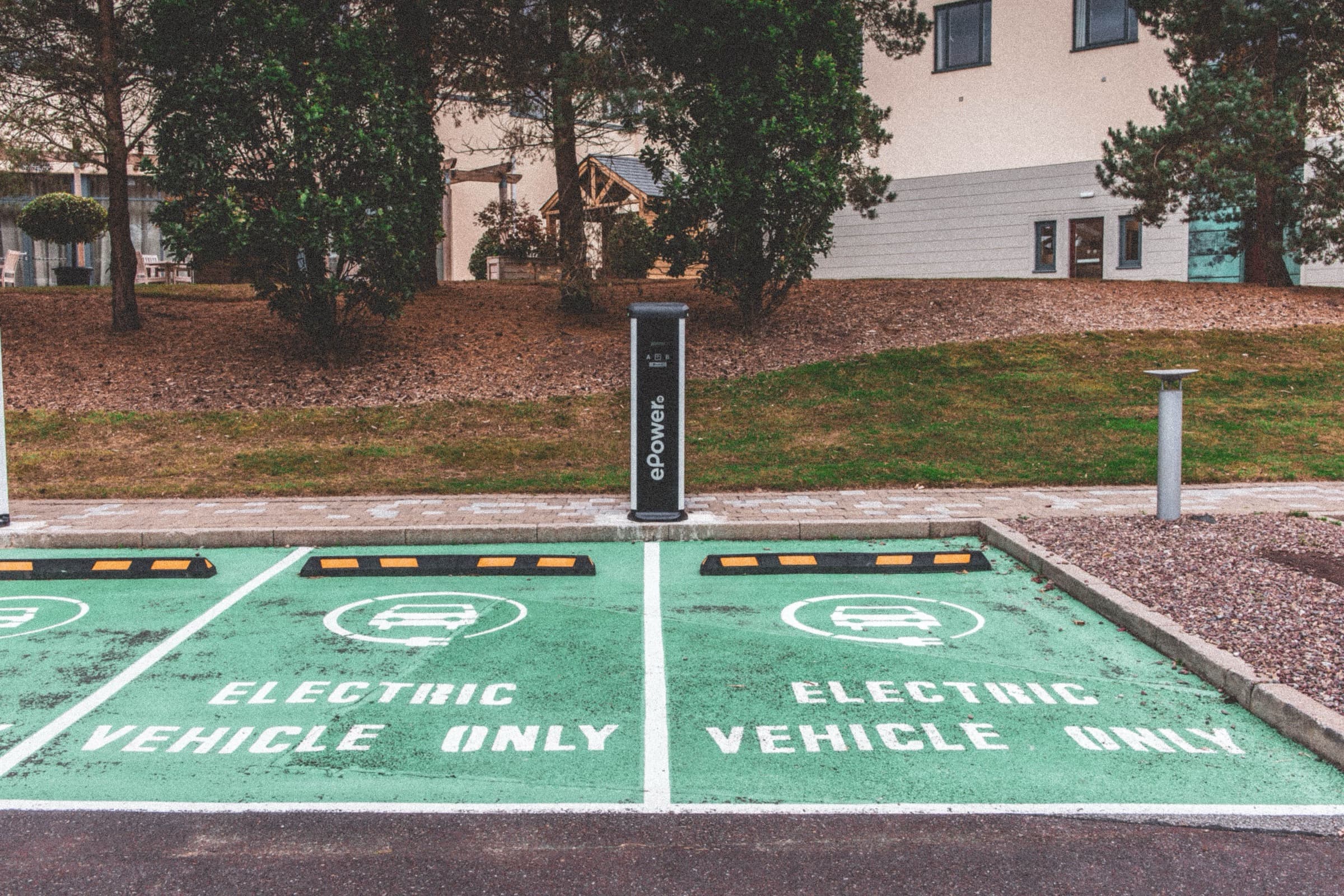 Zielone miejsca parkingowe dla samochodów elektrycznych ze słupkiem ładowania