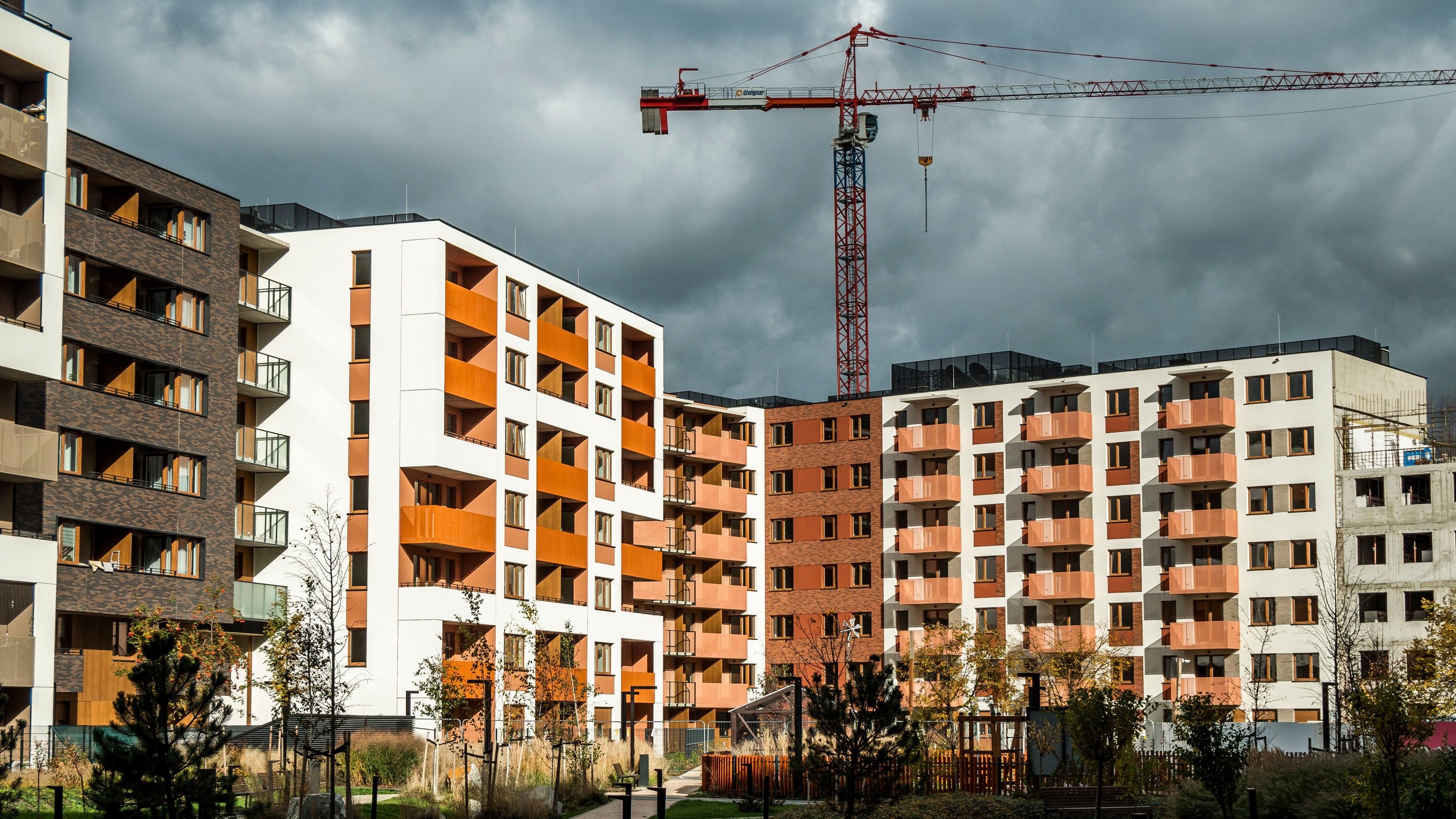 Nowe osiedle bloków mieszkalnych z żurawiem budowlanym — inwestycja deweloperska w trakcie budowy