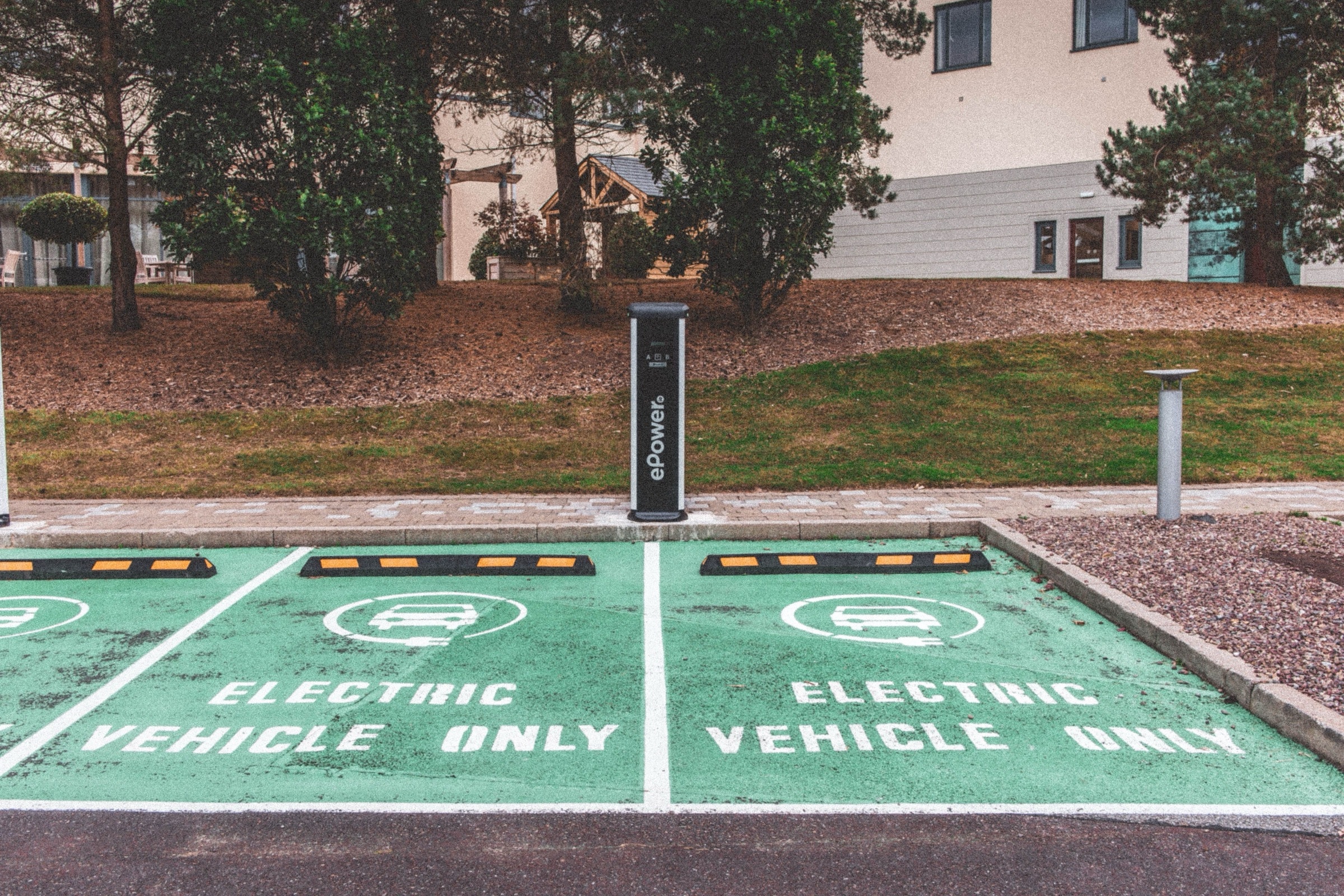 Zielone miejsca parkingowe dla samochodów elektrycznych ze słupkiem ładowania